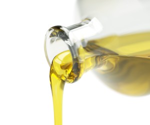 Pouring olive oil out of the bottle isolated on white