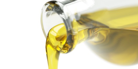 Pouring olive oil out of the bottle isolated on white