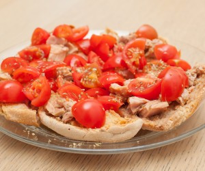 Dried bread called freselle with tuna and tomatoes on wooden table