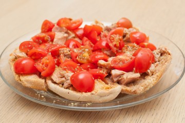 Dried bread called freselle with tuna and tomatoes on wooden table