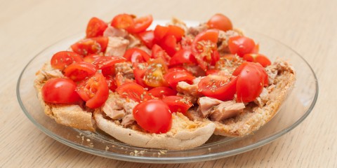 Dried bread called freselle with tuna and tomatoes on wooden table